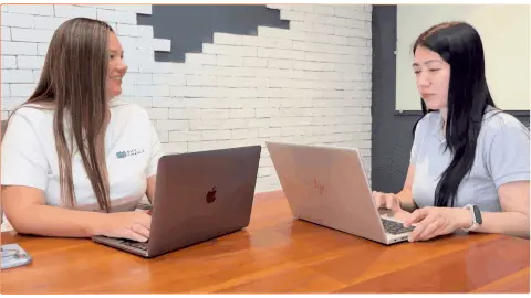 Two OutForce team members collaborating on laptops